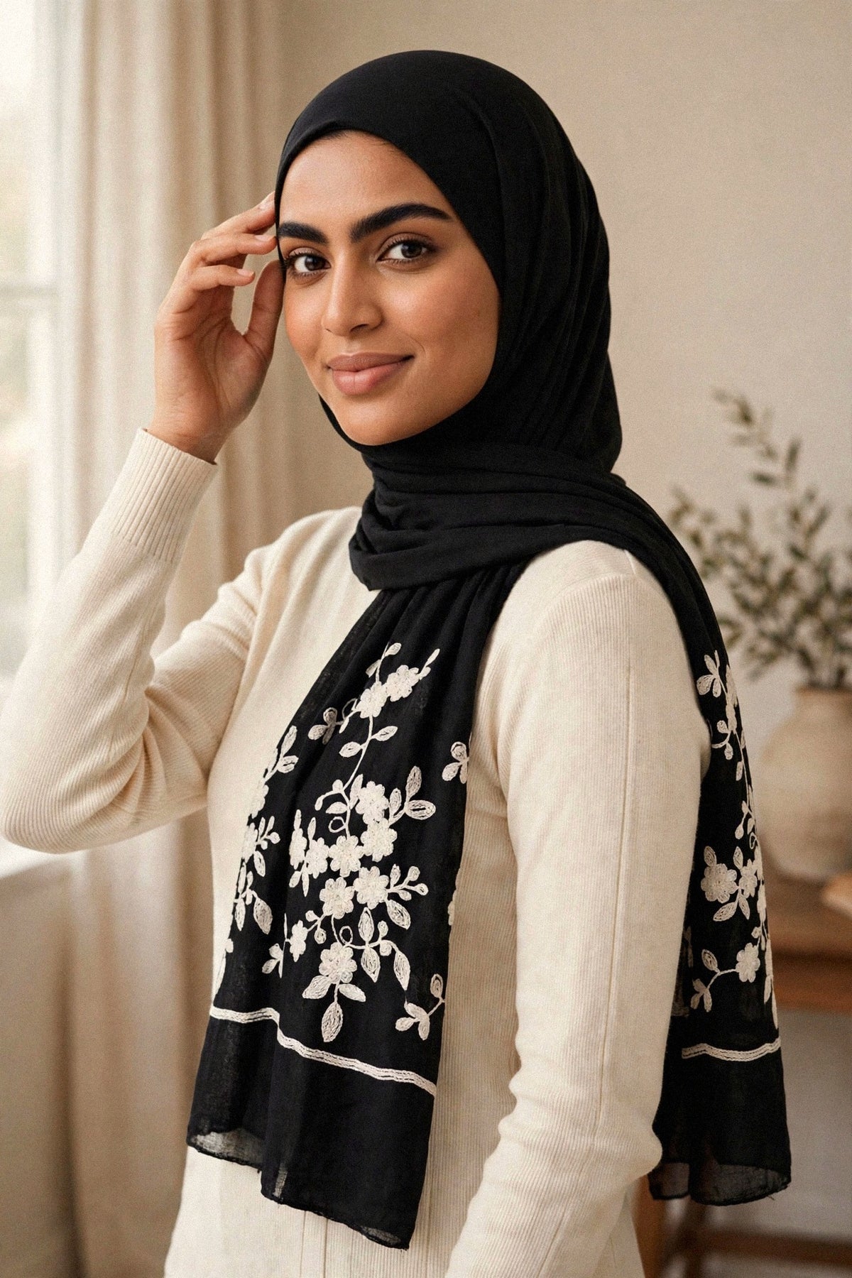 Model wearing the Wildflower hijab — black viscose with white floral embroidery on both ends — lifestyle view